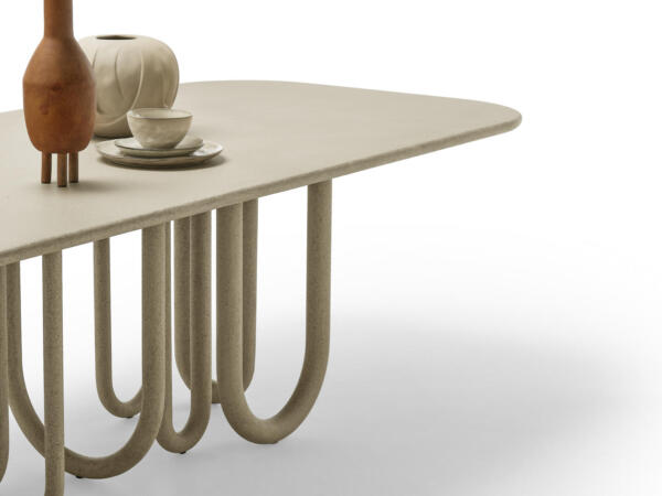 Ein moderner Esstisch mit einer ovalen Tischplatte und einer ungewöhnlichen Basis aus gebogenen Stützbeinen, die an Schlangen erinnern und ein geschwungenes, skulpturales Design bilden.